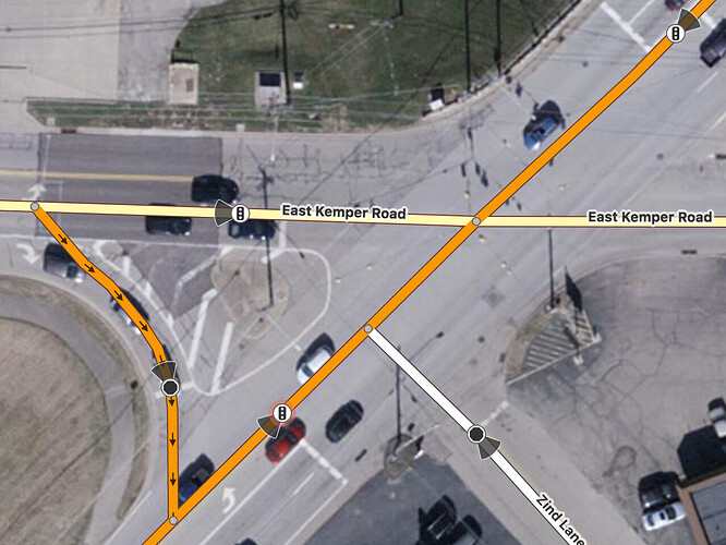 A stop line for a traffic light is located on a primary road before the point where it meets Zind Lane, which only has a stop sign; this is before the point where the primary road meets East Kemper Road, which has traffic lights