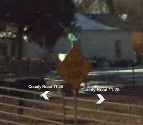 An illegible photo of two plain green rectangular street name signs mounted above a Dead End warning sign.