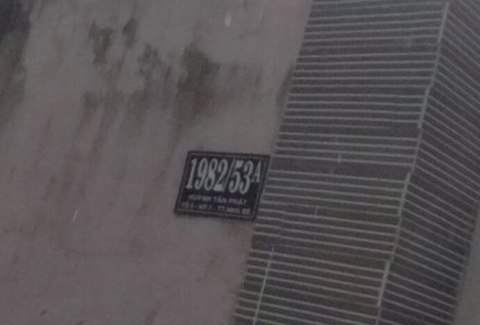 A black house number sign on a residential wall reads “1982/53A” in large type above “Huỳnh Tấn Phát, Tổ 3 - KP.7 - TT Nhà Bè”.