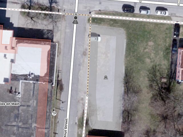 An unmarked gravel parking lot borders the street for almost its entire length, interrupting the sidewalk with enough room for a dozen cars parked side by side. (Orthoimagery courtesy of the Ohio Statewide Imagery Program in the public domain.)