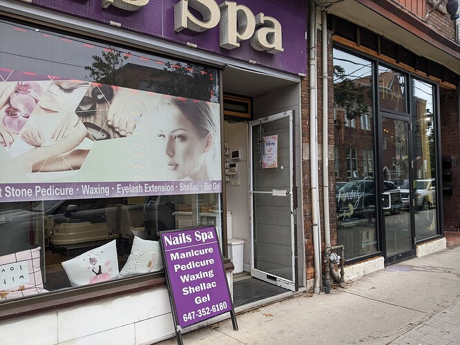 Photo of a storefront taken from a sidewalk. There is a paper sheet posted on the open door on which the wifi network name and password are printed