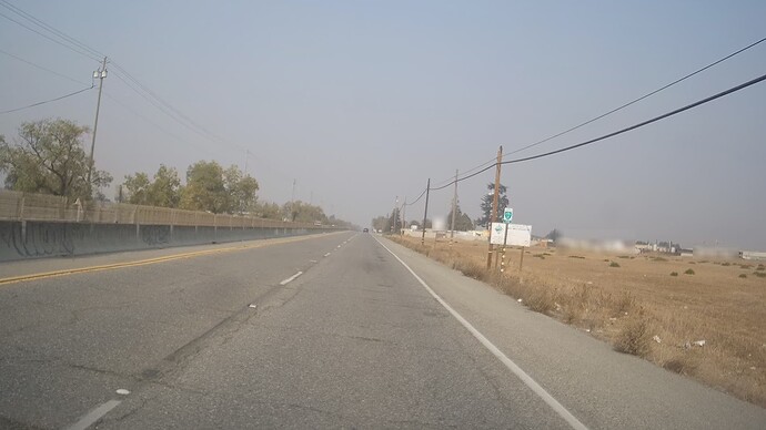 A sign marks the beginning of San José Bike Route 11 along a four-lane expressway with a median barrier. A sign just after it (blurred out) indicates a speed limit of 55 miles per hour.