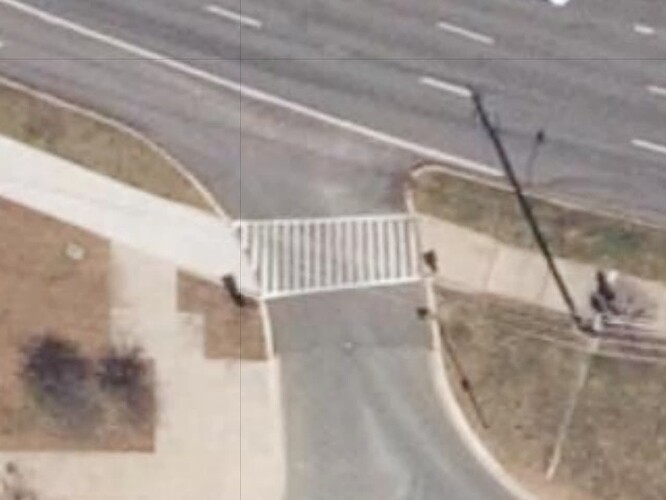 A sidewalk crosses a parking lot entrance road with lowered curb cuts and ladder crosswalk markings. (MD Latest 6 Inch Aerial Imagery, DoIT, MD iMap, MDP)