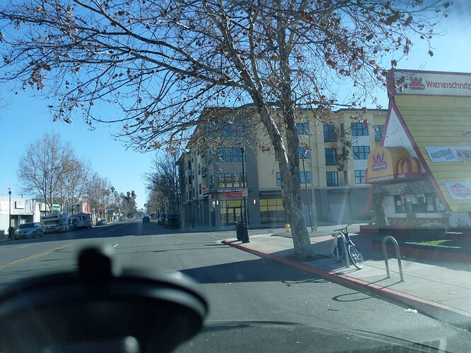 At a T-intersection, there is an unmarked crossing across the cross street and no positive indication of a crossing across the main street. The double yellow centerline going down the main street breaks only for the cross street but not for any crossings beside it. (© 2021 Nikki Diaz, CC BY-SA 4.0.)