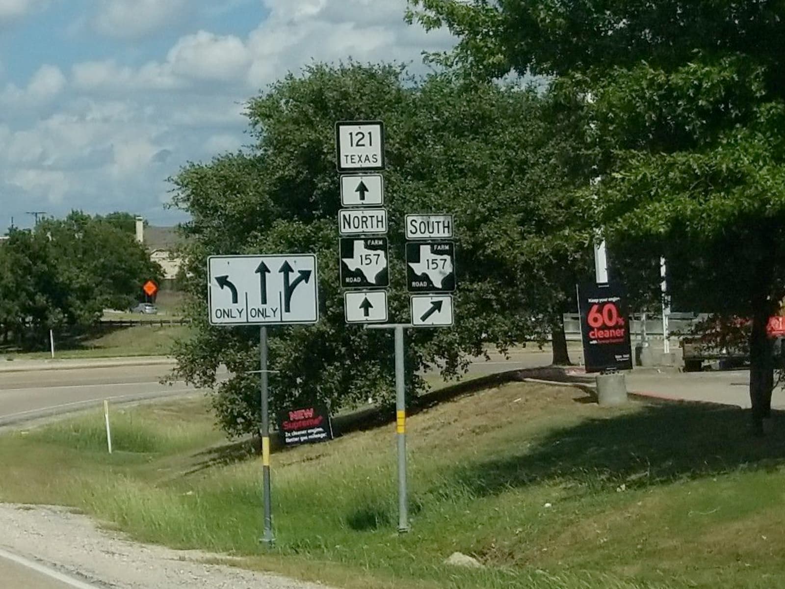 A sign assembly consisting of a State Highway 121 shield, with the name “TEXAS” below the number 121, as well as two Farm to Market Road shields in the shape of Texas.